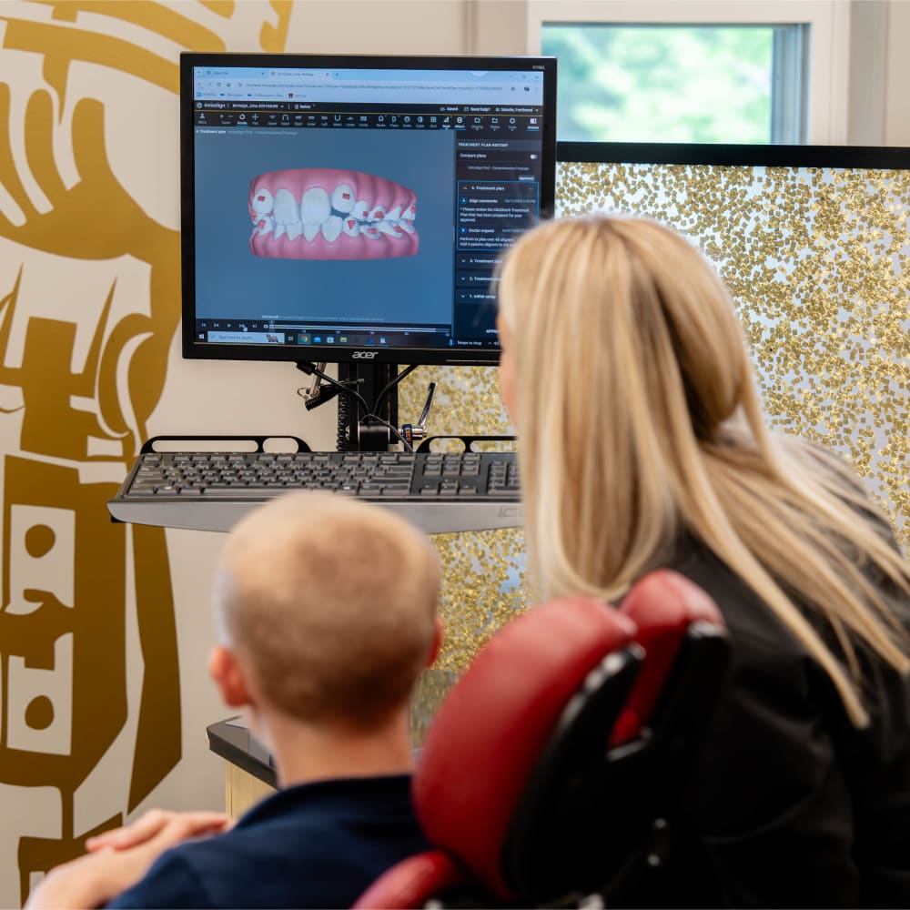 A team member of Sturbridge Orthodontics goes over a young patient's scan with them.