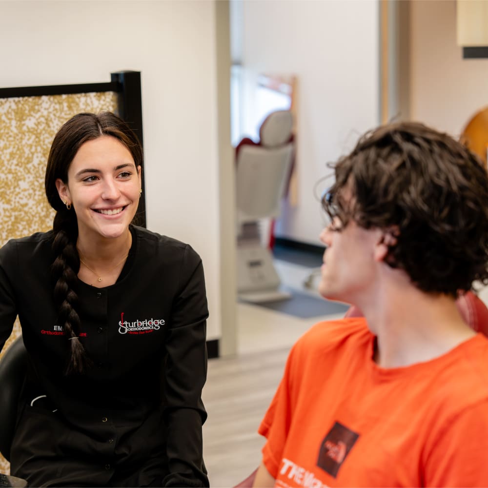 A team member at Sturbridge Orthodontics chats with a teenage patient.