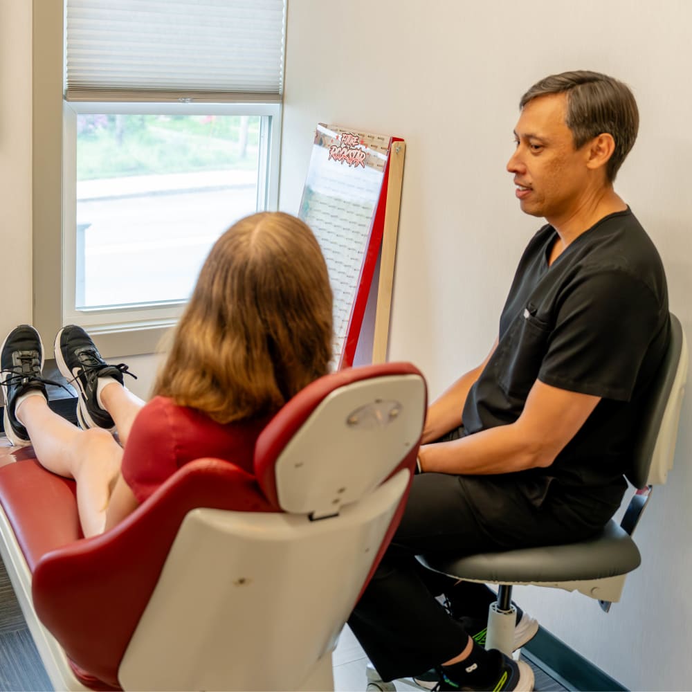 A teenage patient is in the exam chair chatting with Dr. Sabelis.